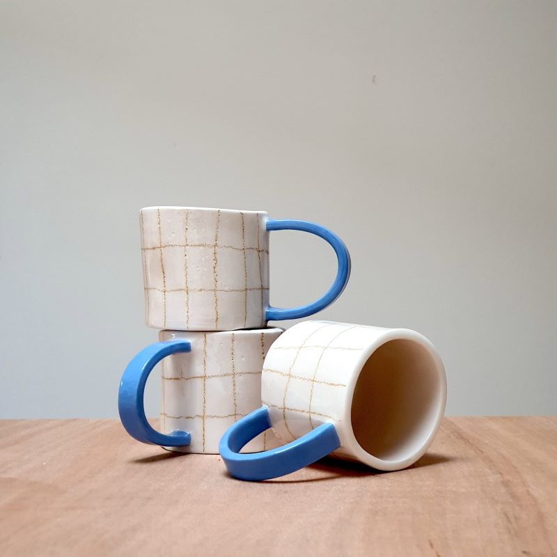 Odeon Studio Karierter Becher mit blauem Henkel